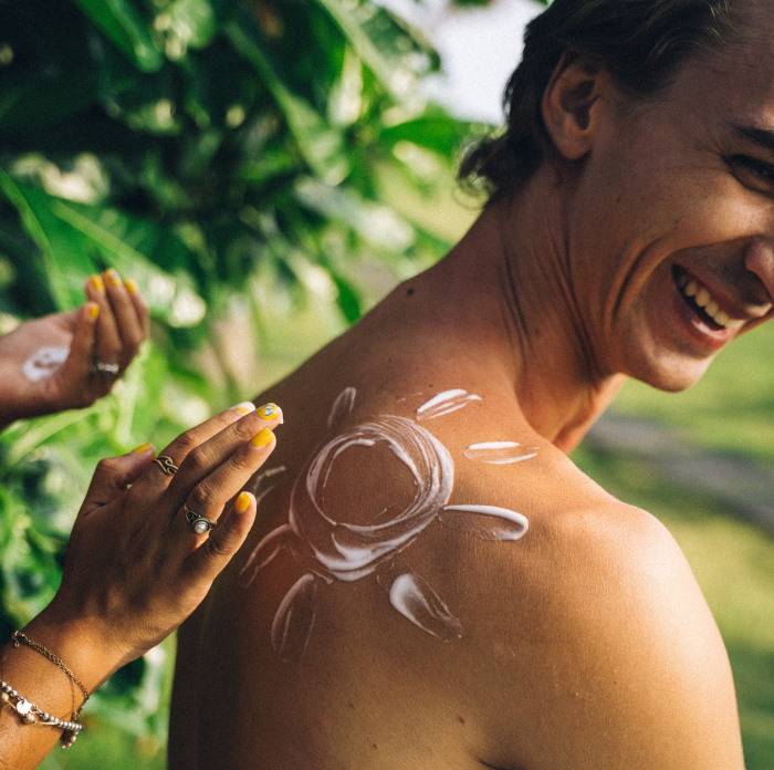 Een man die wordt ingesmeerd met zonnebrand